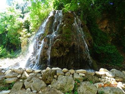 Vue sur l'imposante cascade entourée de végétation et recouverte de mousse