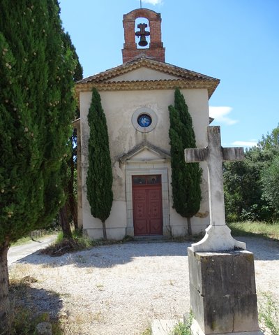Façade principale de la chapelle avec vue sur une croix en pierre, un clocher sur le haut du bâtiment