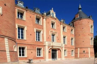 Vue sur la façade du château avec ses briques rouges, ses fenêtres entourées de moulures et ses toits d'ardoise