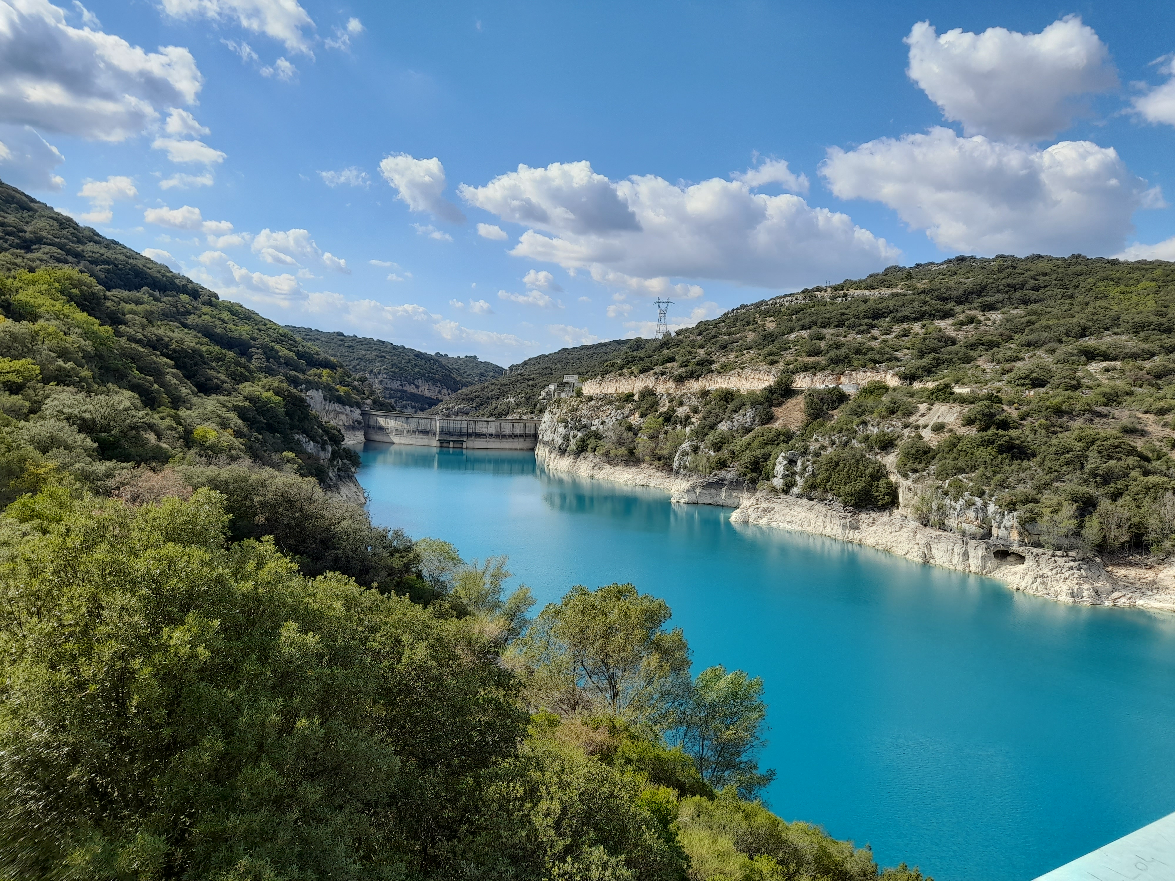 Vue sur le barrage, les berges calcaire et les eaux turquoises du lac entouré de végétation méditerranéenne