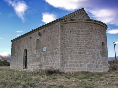Vue sur l'arrière de la chapelle en pierre avec une petite croix en fer